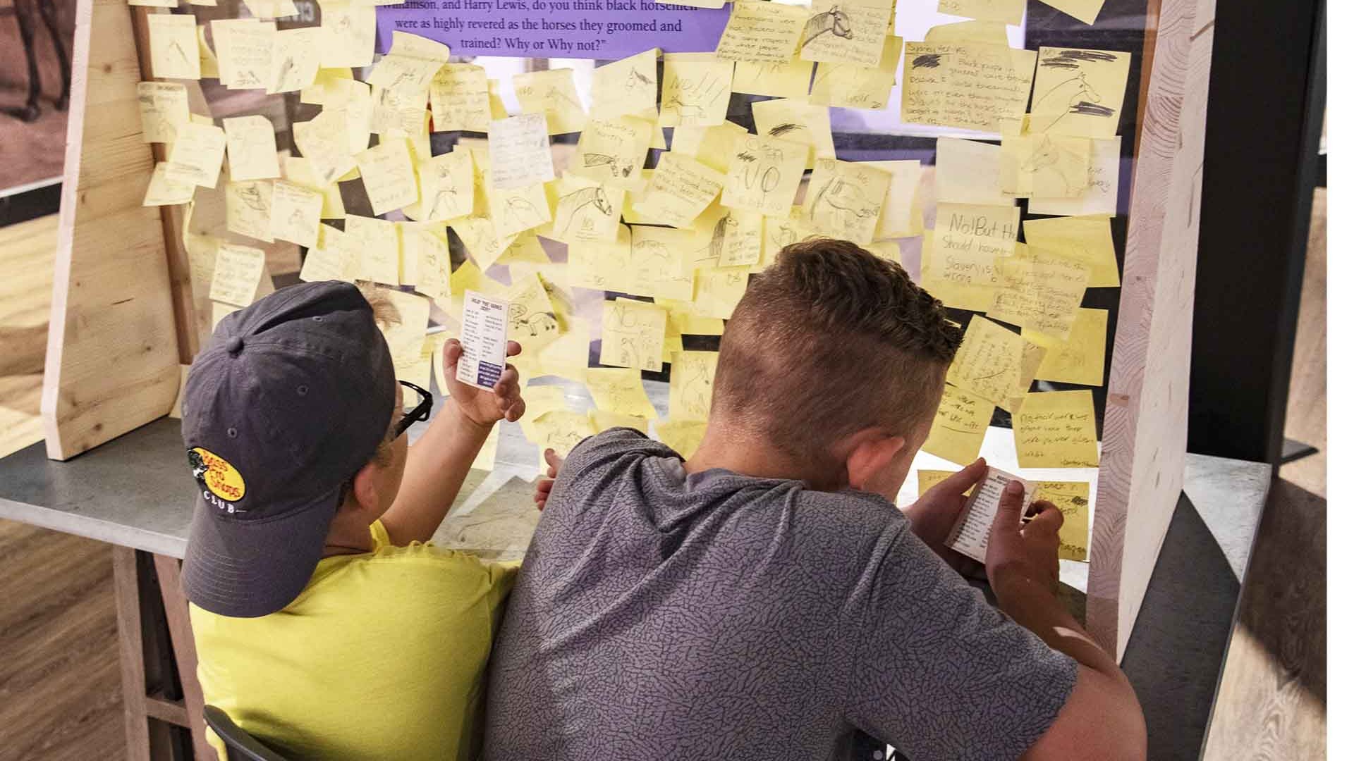 boys read other visitors' notes in museum exhibit